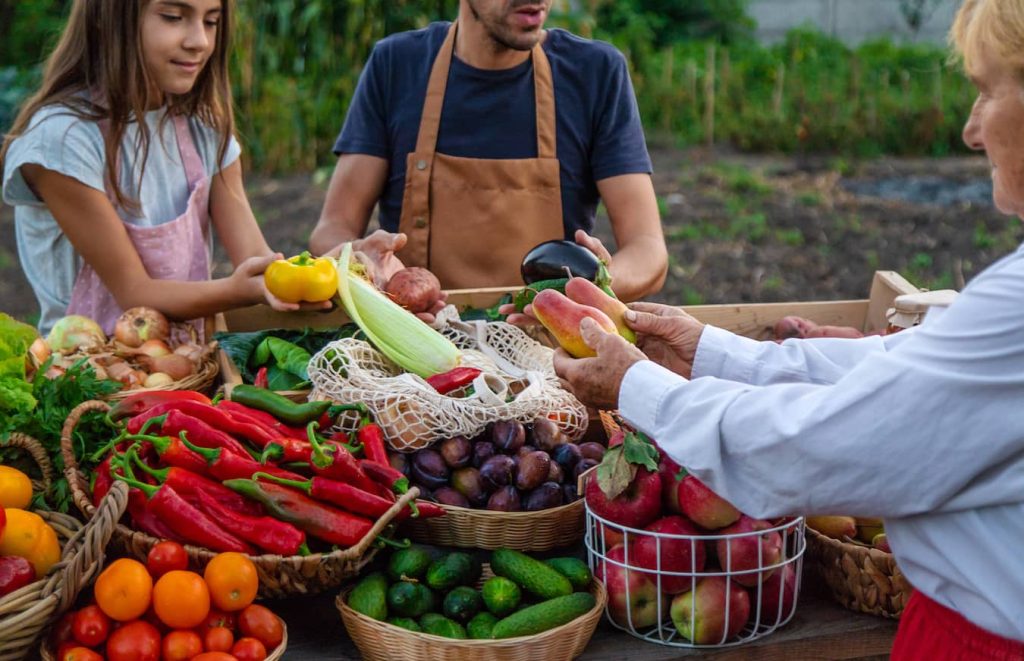 people around a table full of fresh fruits and vegetables